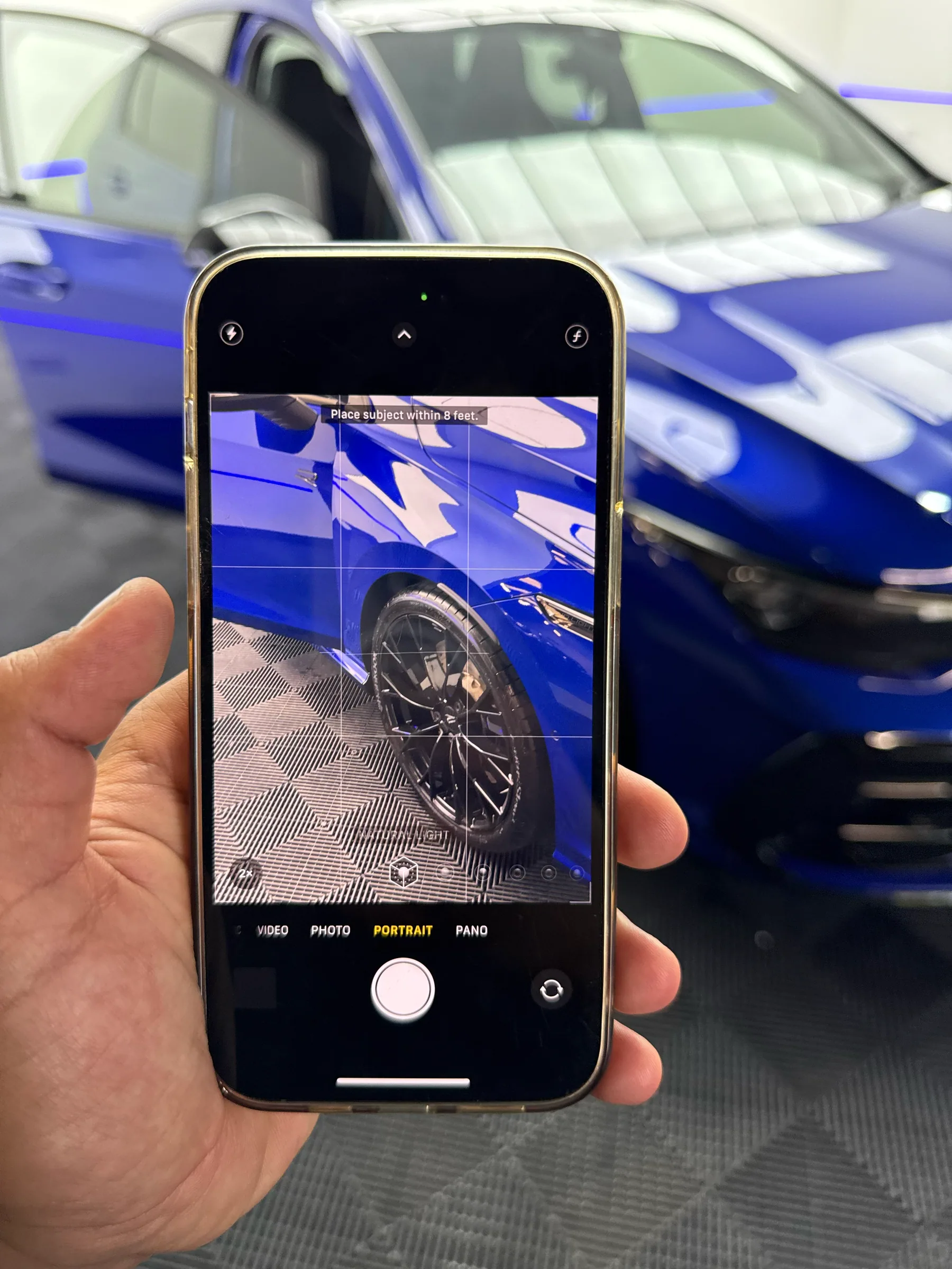 Blue vehicle paint and wheel detail being checked through a phone camera